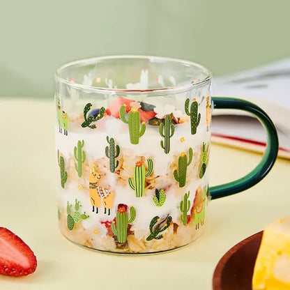 A clear glass cactus glass tea mug with a dark green handle and playful cactus and llama pattern decorbites cactus glass