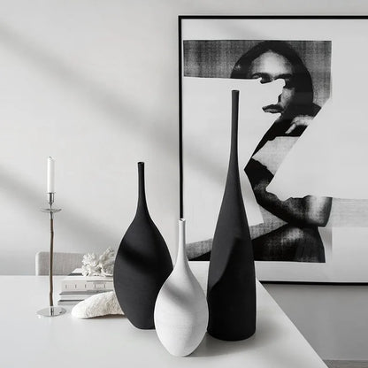 Three minimalist matte black and white ceramic vases with sleek elongated forms for nordic home decoration