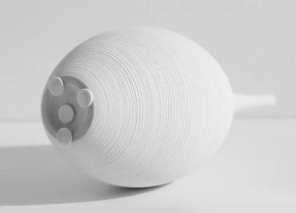 White textured ceramic capiron zen vase with narrow neck and three circular indentations for home decoration