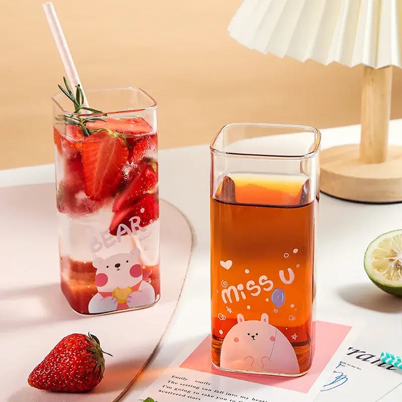 Clear rectangular glass coffee mugs with colorful cartoon bear decals filled with strawberry and amber drinks