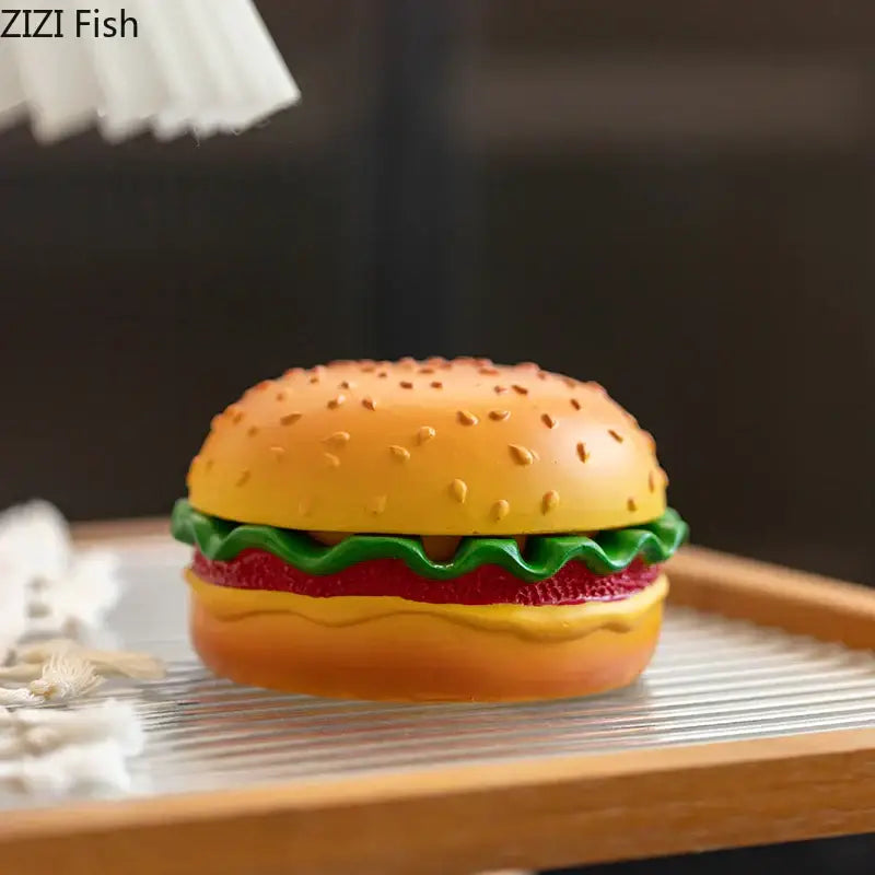 A vibrant cartoon burger ashtray in yellow and green resin shaped like a hamburger for office table decor