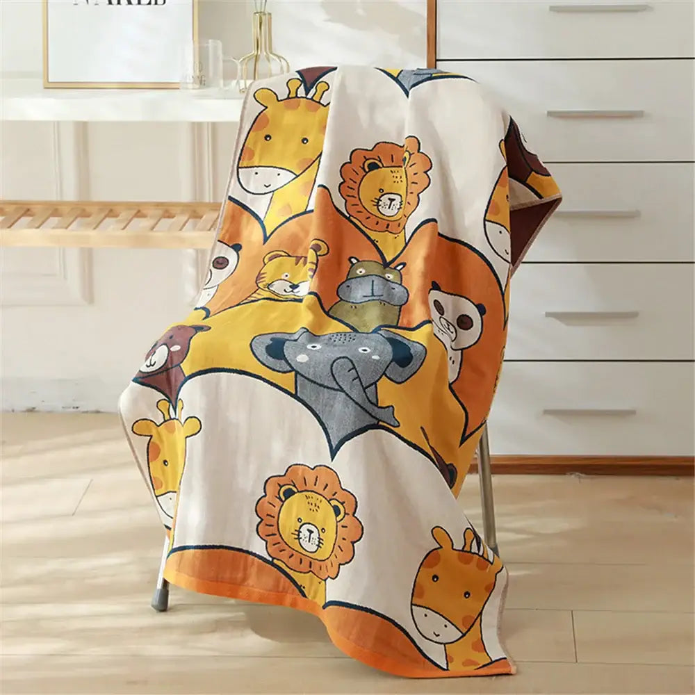 A soft white decorbites cotton gauze bath towel with playful orange yellow and gray cartoon animals for nursery decor