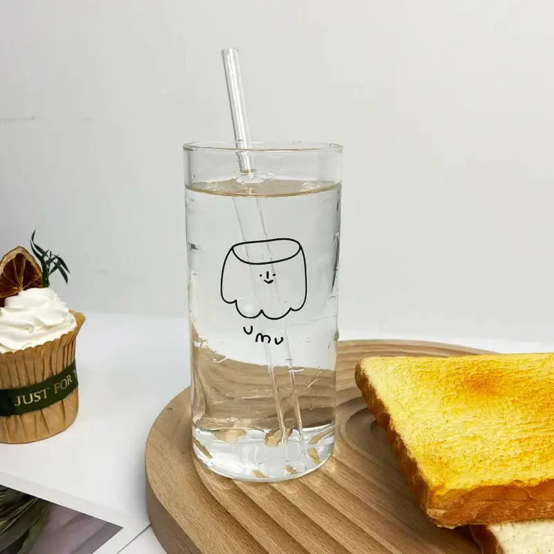 Clear glass cup with black line marshmallow drawing and yum text filled with water and clear straw decorbites cartoon glass