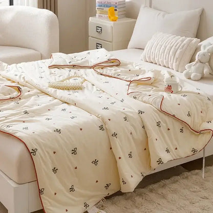 Cream-colored quilted cartoon rabbit off white cooling summer blanket with black bow heart patterns and red piping edges