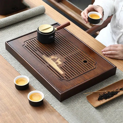 Dark brown bamboo tea tray with carved deer design and slatted drainage area for dining room use