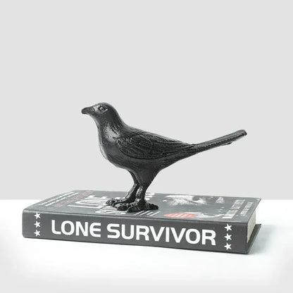 Black matte cast iron bird decoration perched on a book for elegant living room decor and iron bird display