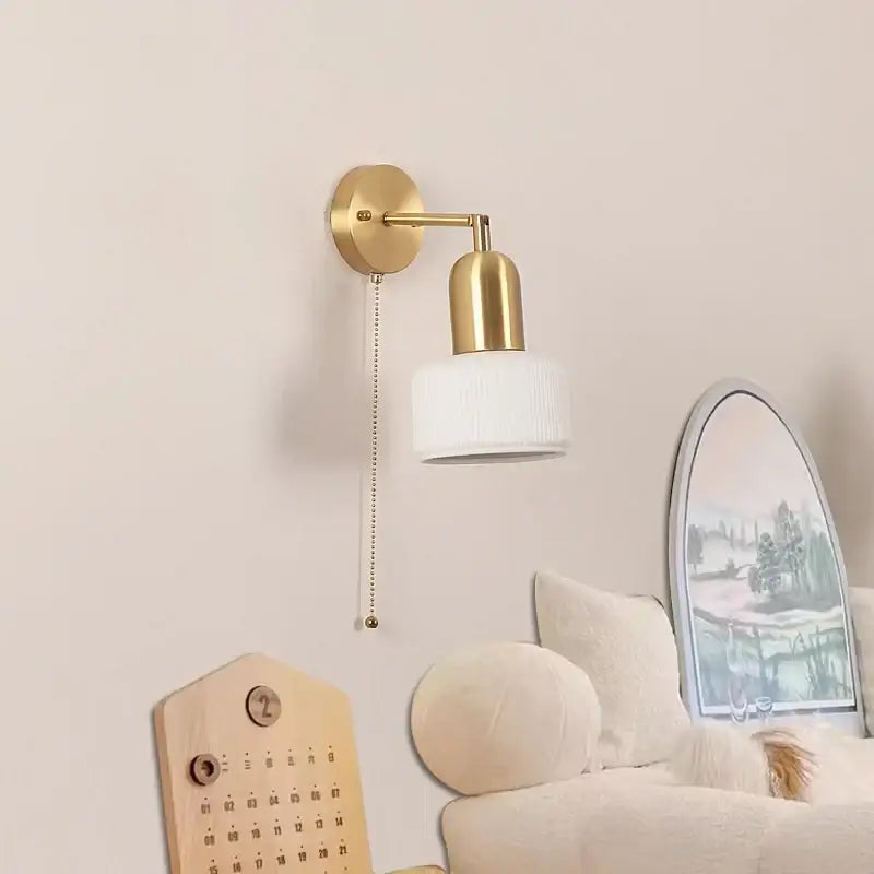 Gold-finished ceramic art wall lamp with white ribbed glass shade and pull-chain switch for adjustable bedroom reading light