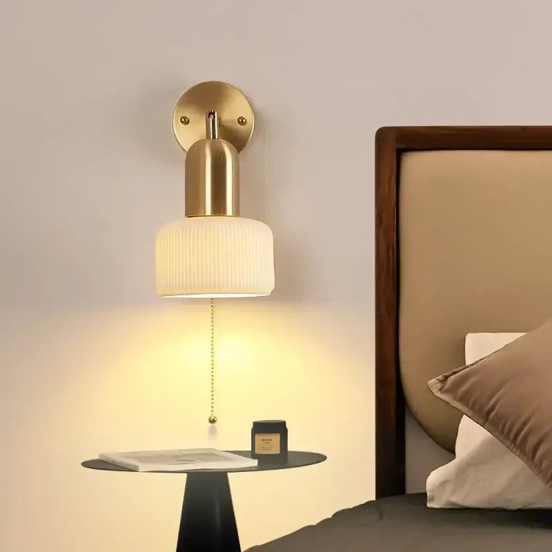Gold-toned ceramic art wall lamp with ribbed off-white glass shade and pull-chain switch for adjustable reading light