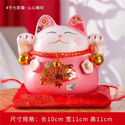 Pink ceramic maneki neko piggy bank with floral ear decorations gold bells and red cord by decorbites ceramic maneki