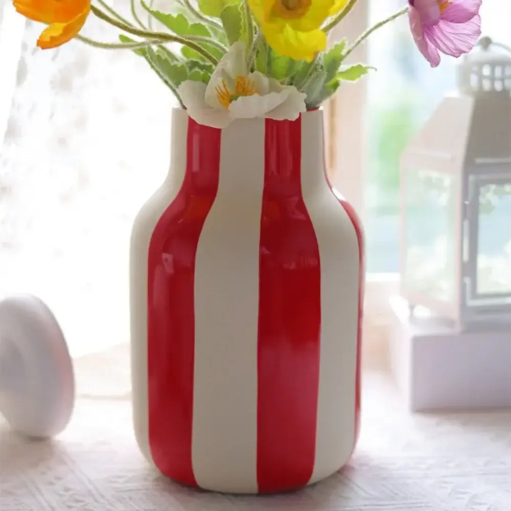 Glossy red and white striped ceramic vase holding a bouquet of yellow pink and white flowers ceramic vase black red striped