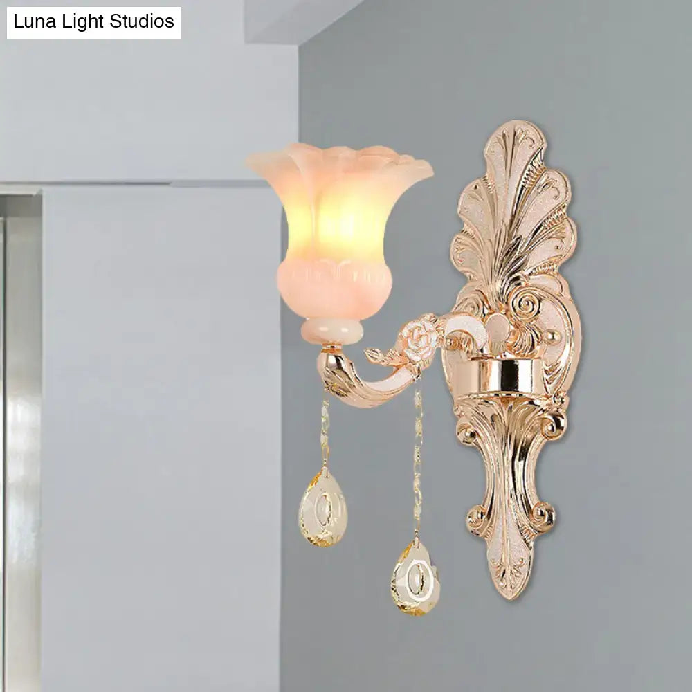 Chic gold and pink crystal wall lamp featuring a gold-toned ornate sconce with peach glass flower shade and crystal pendants