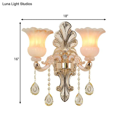 Gold-toned ornate wall lamp with two peach glass shades and crystal teardrop pendants for bedroom decor