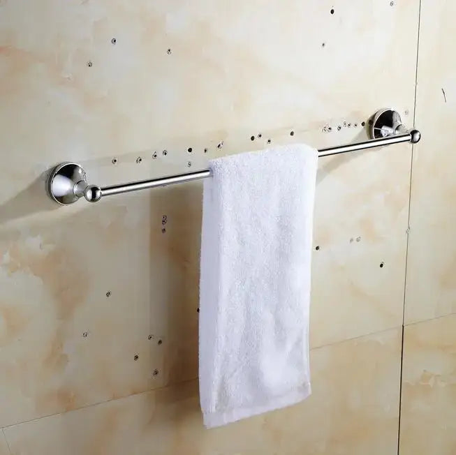 Shiny chrome crystal bathroom set towel rack with spherical end caps holding white terry cloth towel decorbites brass
