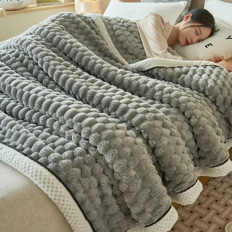 Soft gray coral fleece blanket with raised pom-pom texture and white ribbed trim for bedroom use
