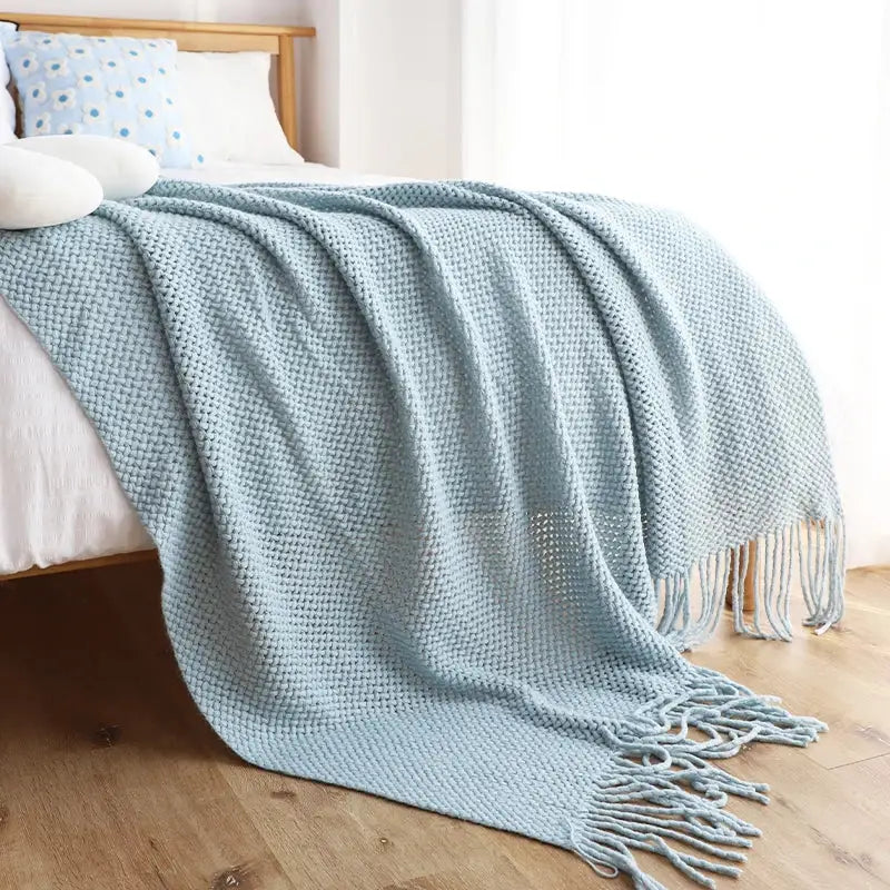 A soft light blue knitted leisure blanket throw with a textured waffle pattern and tassels for bedroom decorbites decor
