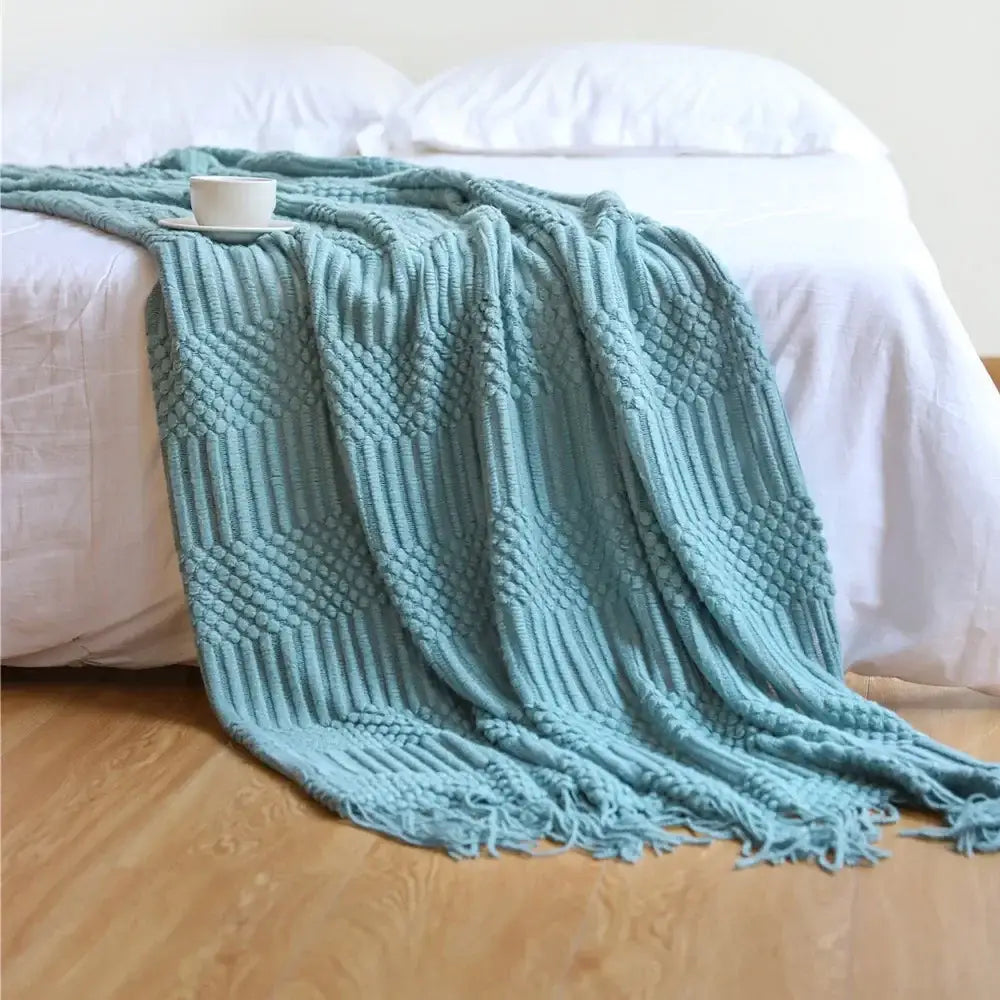 A soft teal knitted sofa blanket with a textured diamond pattern and fringed edges perfect for decorbites cozy knitted decor