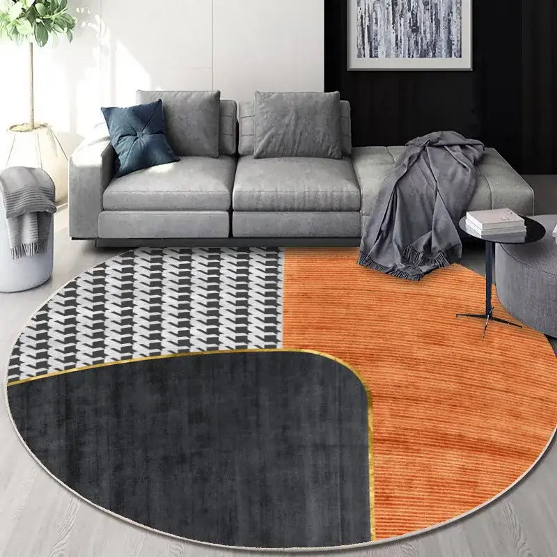Modern round floor mat with bold black white and warm orange geometric design trimmed in gold decorbites circular geometric cashmere