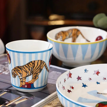 A ceramic cup from decorbites circus troup kids tableware set featuring blue and white stripes with an orange tiger design
