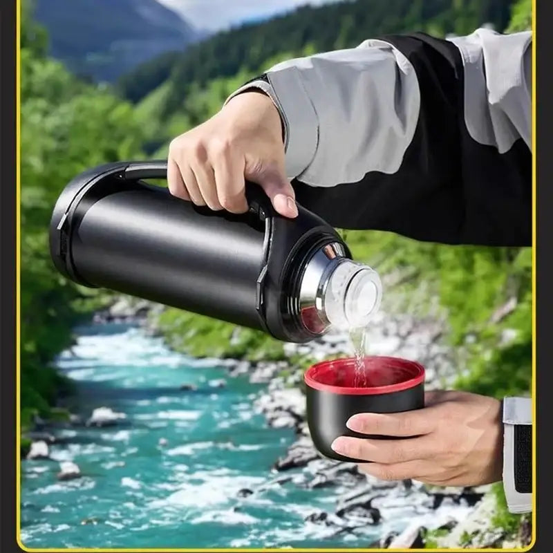 Classic black and red vacuum thermos flask being poured into a matching cup for outdoor kitchen use