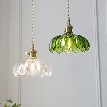 Two hanging pendant lights with classic glass petal and vibrant green designs, brass hardware, and twisted cords for dining rooms