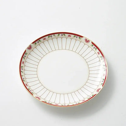 A white ceramic saucer with a delicate red and gold floral border from a classical gold-striped ceramic cup and saucer set