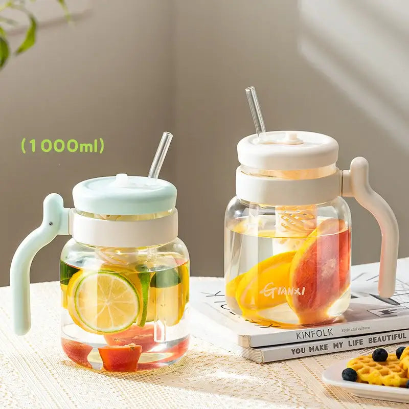 Clear 1000ml glass tumbler with handle and straw featuring a light mint green lid filled with citrus infused water