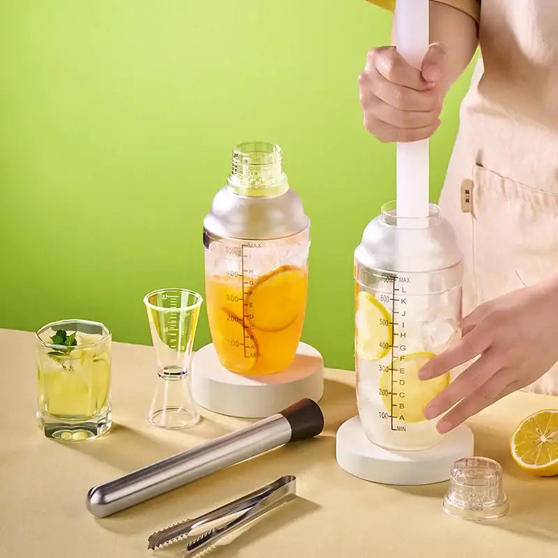 Clear plastic cocktail shaker with measurement markings and yellow liquid inside for decorbites beverage mixer use