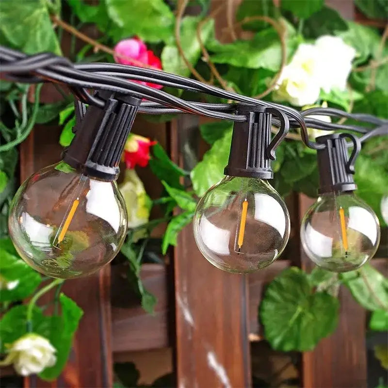 Clear glass globe g40 led string lights with black plastic fixtures and visible led filaments on dark cord decorbites g40 led