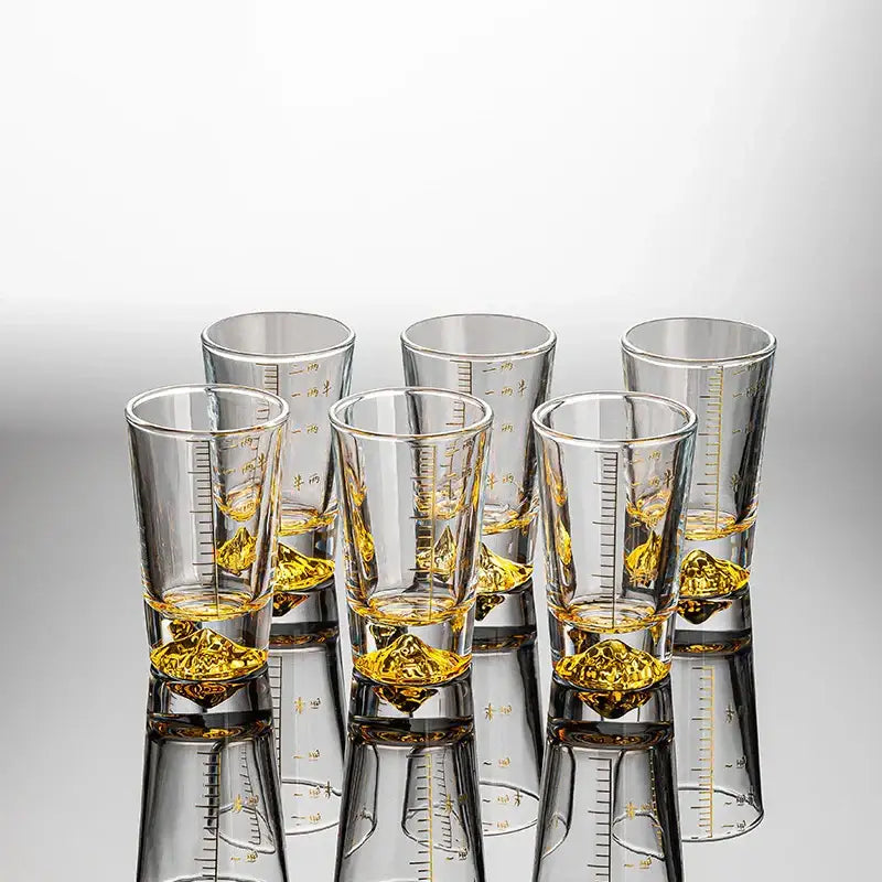 Clear glass liquor cup set with gold measurement markings and golden liquid by decorbites clear glass decor for dining room