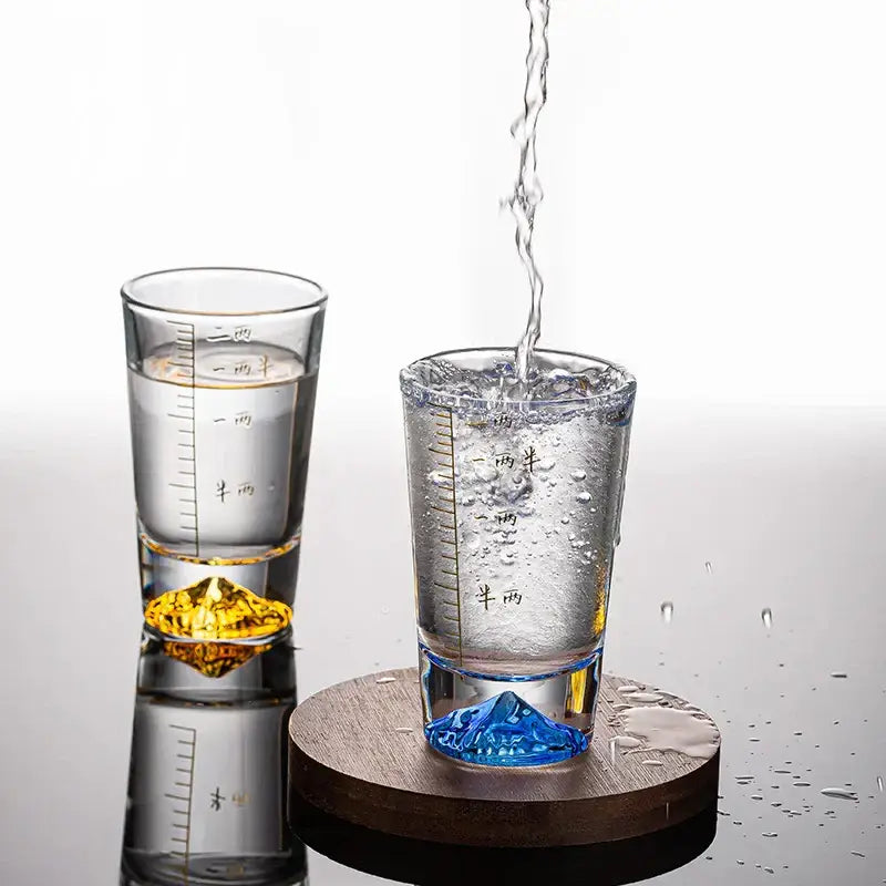 Clear glass liquor cup set with measurement markings and colorful mountain-shaped gold and blue bases decorbites clear glass