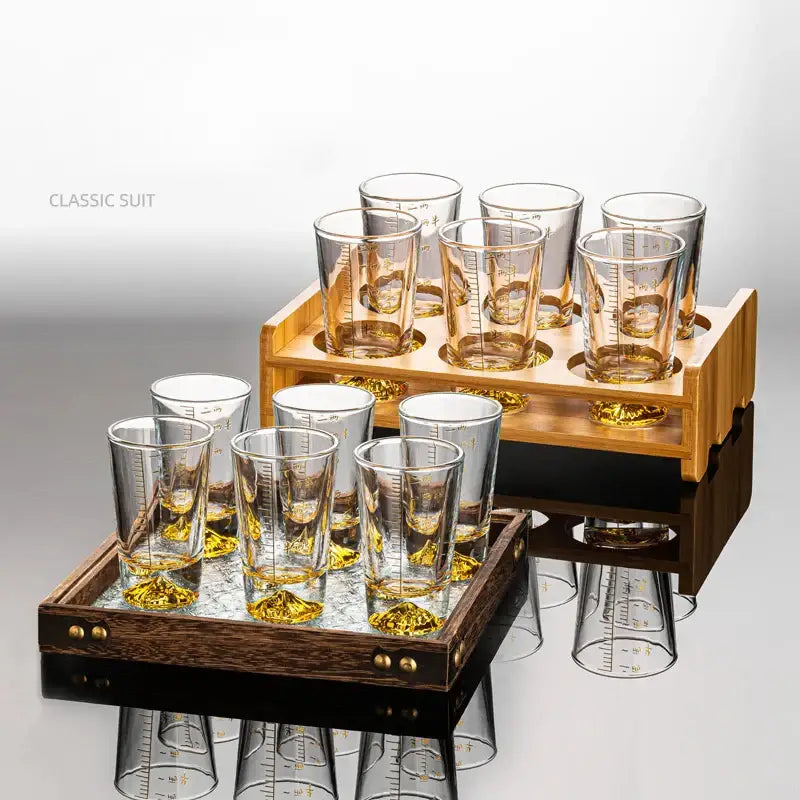 Set of clear glass liquor cup with measurement markings and gold-colored bases displayed in wooden trays decorbites clear glass