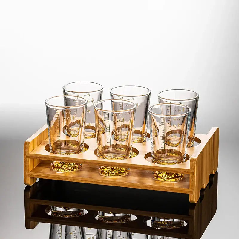Set of six amber-tinted clear glass liquor shot glasses with measurement markings in a light wood tray for decorbites clear glass