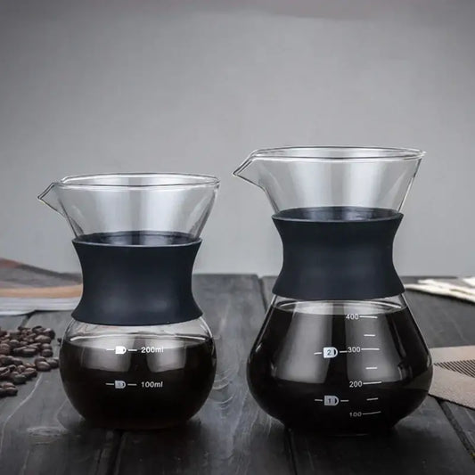Two clear glass pour over coffee makers with black silicone bands and stainless steel filters filled with brewed coffee
