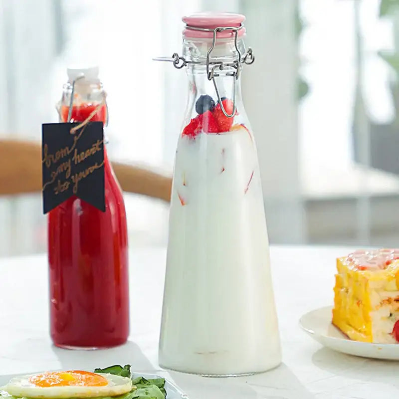 Clear glass storage bottle with pink metal clasp lid filled with white liquid and berries for decorbites glass storage