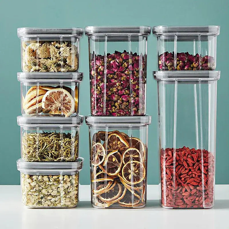 Clear decorbites hermetic food storage containers with gray lids filled with dried herbs and fruits for kitchen preservation