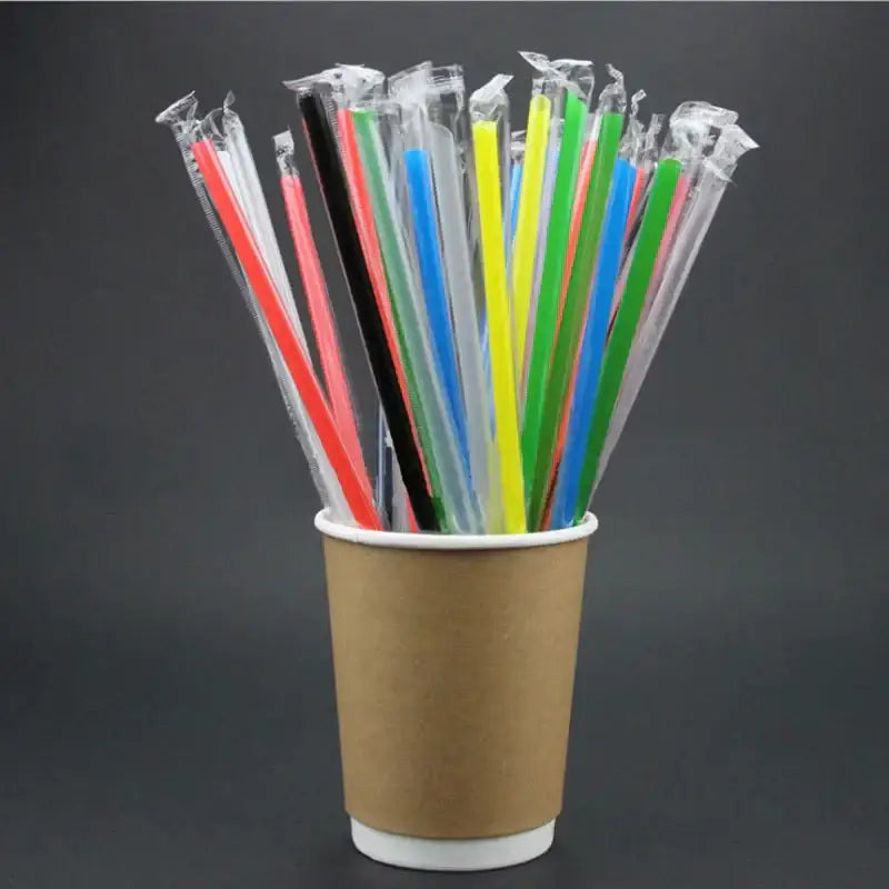 A cup filled with colorful decorbites clear individually wrapped drinking straws made of plastic for kitchen use