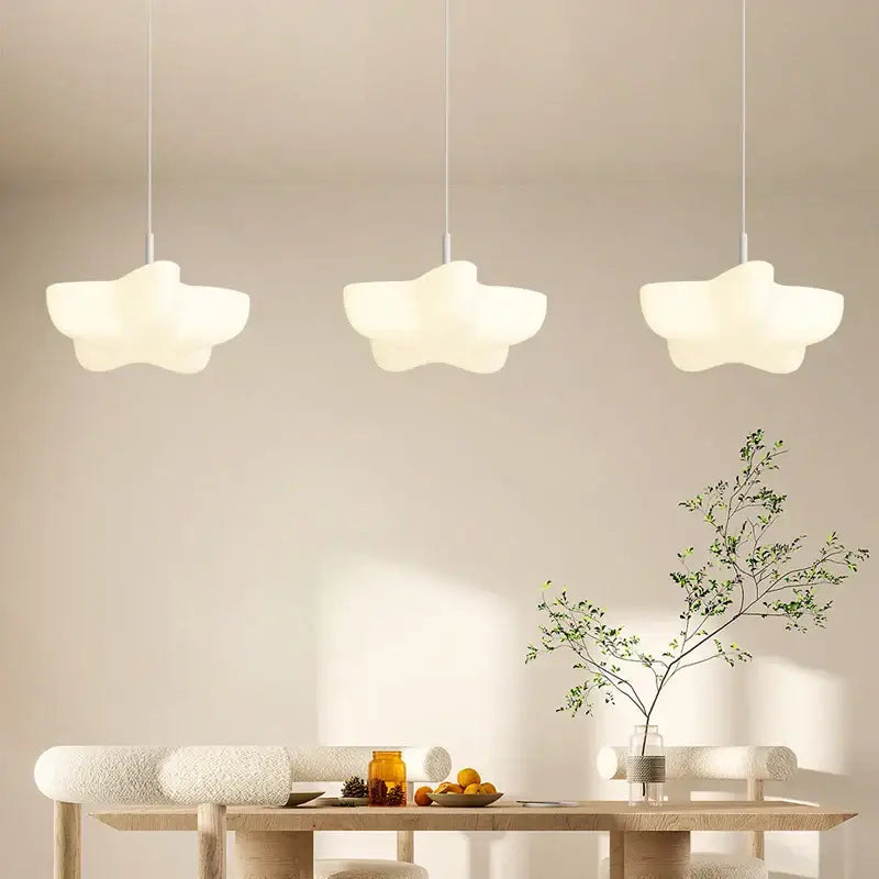 Three off-white cloud white modern pendant lights with matte finish hang above a wooden dining table decorbites cloud white chandelier