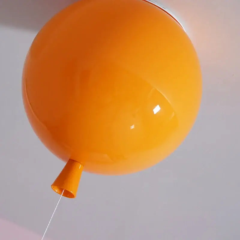 Vibrant orange balloon-shaped ceiling sconce lamp with glossy finish and matching tapered base for bedroom decor