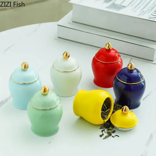 Set of colorful ceramic storage jars with gold lids and decorative finials ideal for kitchen tea caddy use