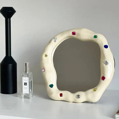 Cream ceramic makeup mirror with irregular edge adorned with colorful square and heart-shaped gemstones for bedroom use