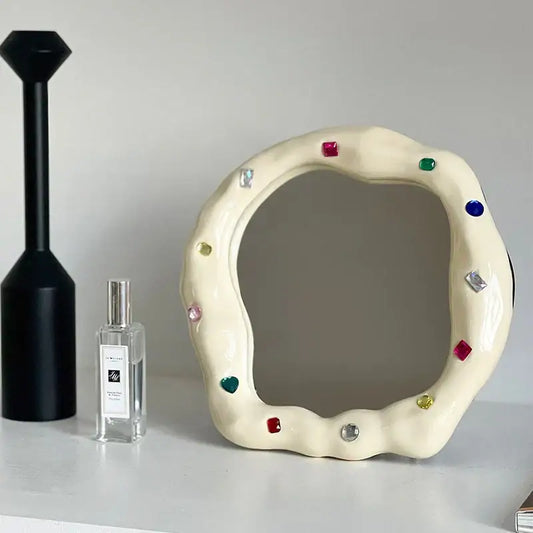 Cream ceramic makeup mirror with irregular edge adorned with colorful square and heart-shaped gemstones for bedroom use