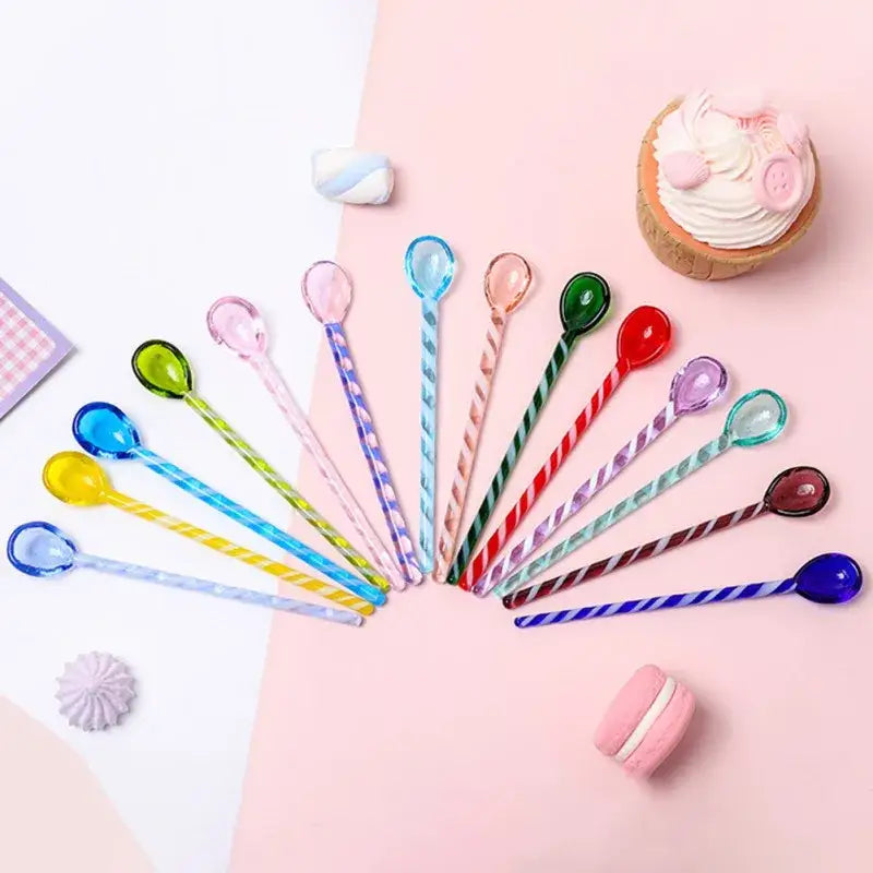 A set of colorful glass stirring spoons with translucent bowls and striped handles arranged in a fan shape by decorbites colorful glass