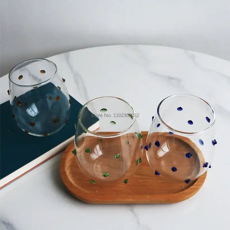 Three clear glass stemless wine glasses with colorful gold green and blue glass wave dots for dining room use