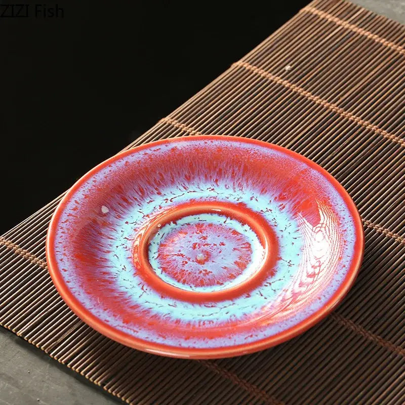A colorful glazed porcelain saucer with a vibrant swirling red and blue design in a tea cup saucer set