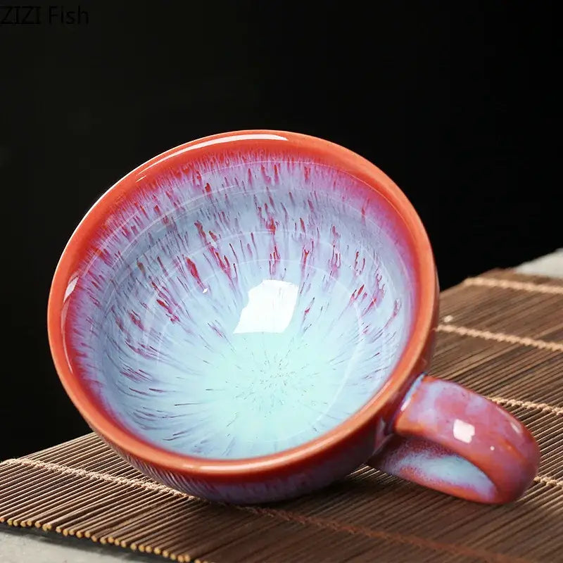 A colorful glazed porcelain tea cup and saucer set with a glossy gradient from deep red to light blue and reddish-brown streaks