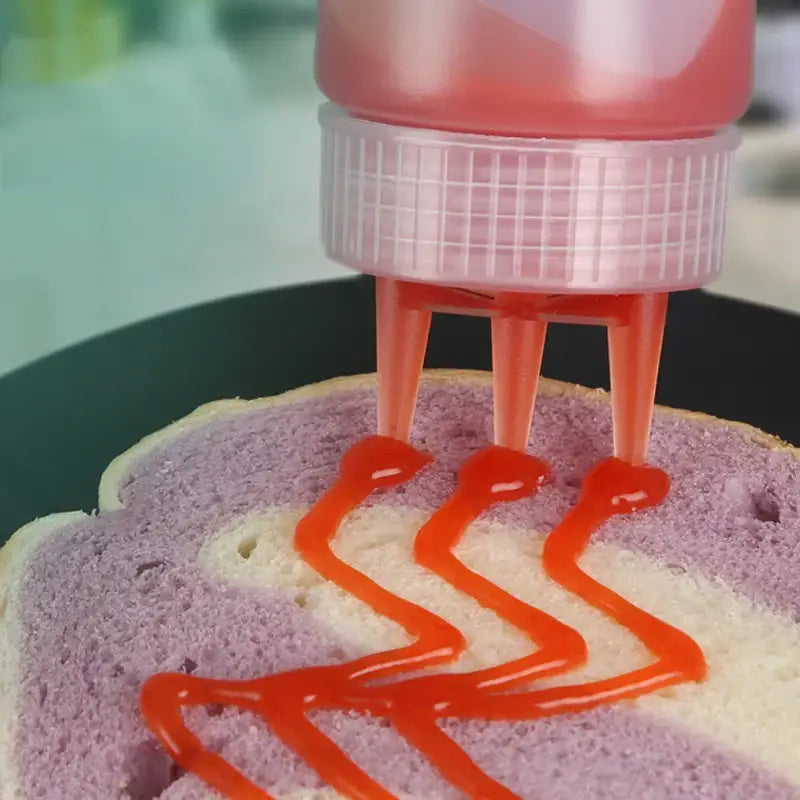 Pink plastic decorbites condiment squeeze bottle set with grid cap and four orange nozzles dispensing red sauce