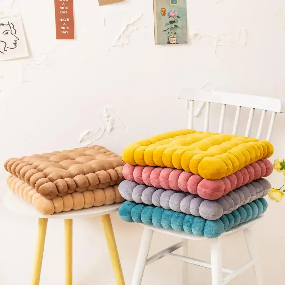 Stacked colorful quilted cookie biscuit cushions in vibrant yellow pink purple and teal for living room use