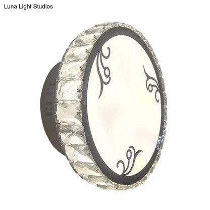 Contemporary black circular wall light with clear crystal trim and oval white diffuser featuring black swirling patterns