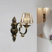 Contemporary wall mounted brass and black ornate wall light with crystal prism lampshade for bedroom use