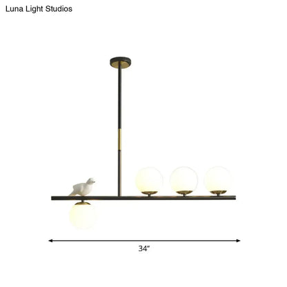 Modern black and brass decorbites linear branch dining pendant light with frosted globes and ceramic bird for dining room island